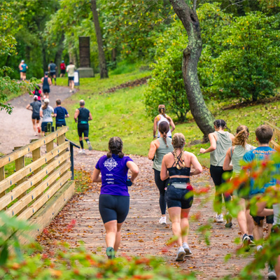 runners crossing wooden bridge on greenway